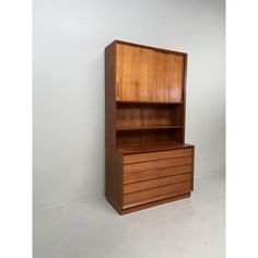 a wooden cabinet sitting on top of a white floor next to a wall with an open door