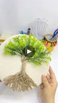 someone is holding up a fake tree on top of a pillow with scissors and other items around it