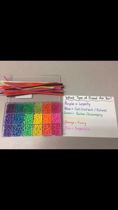 there are many different colored beads in the box and on the table next to it is a note that says what type of friend are you?