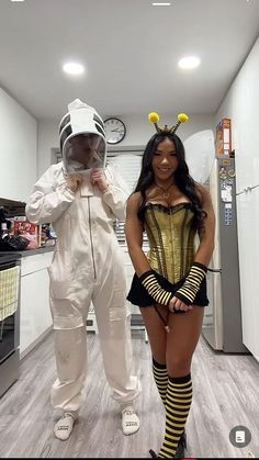 two people dressed in costumes standing next to each other on a kitchen floor, one wearing a bee costume