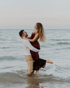 a man carrying a woman on his back while standing in the water at the beach