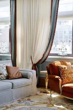 a living room with two couches and a rug in front of a window that has drapes on it