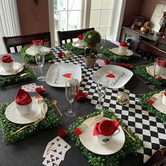 a dining room table set for valentine's day with red roses and greenery