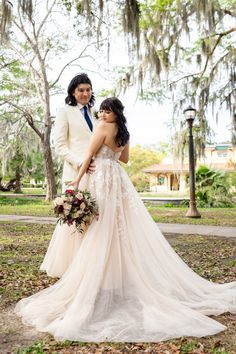 a bride and groom standing in front of trees