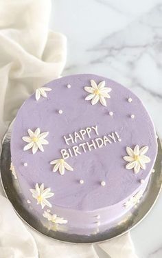 a purple birthday cake with white flowers on it