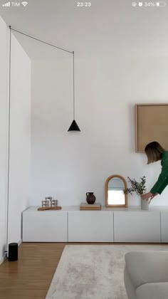 a woman standing on top of a white couch in a living room next to a mirror