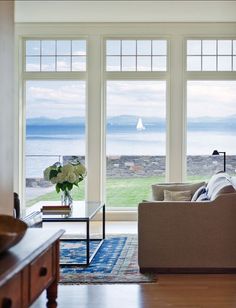 a living room filled with furniture and large windows overlooking the ocean on a sunny day