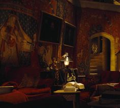 a living room filled with red couches and paintings on the wall next to a lamp