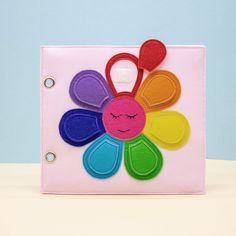 a pink purse with colorful felt flowers on the front, and a smiley face drawn on it