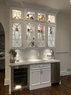 a kitchen with white cabinets and wood flooring, lighted by recessed lights in the cabinet doors