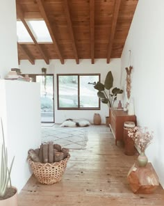 a living room with wooden floors and white walls, plants in baskets on the floor