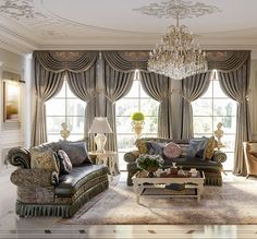 a living room filled with furniture and a chandelier hanging from the ceiling in front of two windows