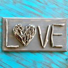 a love sign made out of driftwood on a blue painted wood background with the word love written in it