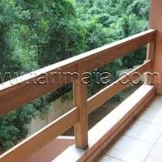 balcony with wooden railing and trees in the background