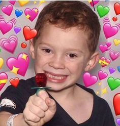 a young boy holding a toothbrush in front of hearts