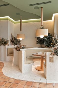 the interior of a restaurant with round tables and planters