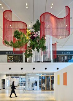 a woman walking through an airport lobby with red and white decorations hanging from the ceiling