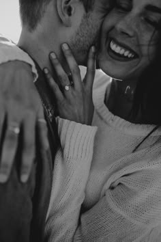 black and white photograph of a couple embracing each other with rings on their fingers in front of the camera