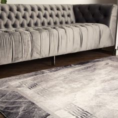 a gray couch sitting on top of a wooden floor next to a rug and chair