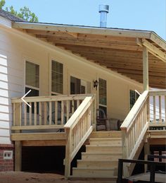 a mobile home with stairs leading up to the front door and second story deck area