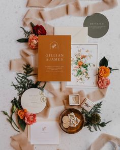 the wedding stationery is laid out on top of some paper and flowers, including roses