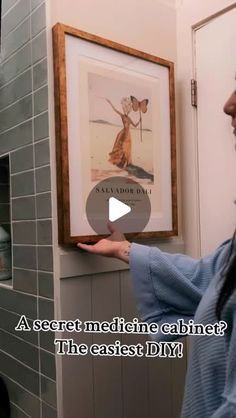 a woman is pointing to a framed poster on the wall