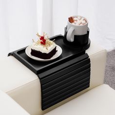 a tray with a piece of cake on it next to a cup of hot chocolate