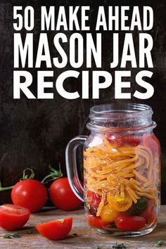 mason jar filled with pasta and tomatoes on top of a wooden table next to other vegetables