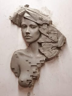 a clay sculpture of a woman's head is shown on a white wall with peeling paint