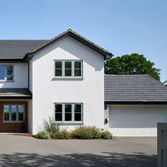 a large white two story house with lots of windows and garage doors in front of it