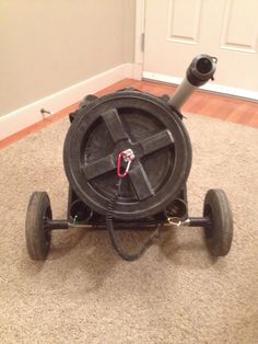 a black wheelbarrow sitting on the floor in front of a door with wires attached to it