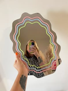 a woman taking a selfie with her cell phone in front of a circular mirror