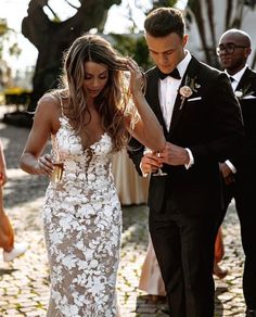 a man in a tuxedo standing next to a woman in a white dress