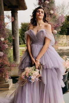 a woman in a purple dress holding flowers