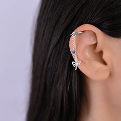 a woman wearing a silver ear cuff with blue stones on the back of her ear