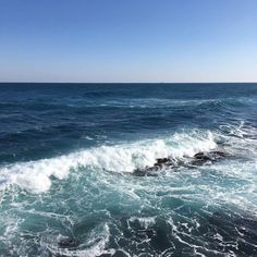 the ocean is blue and green with white foamy waves coming in from the shore