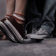 two people standing next to each other with their feet on the ground and one person wearing striped socks