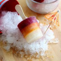 an ice cream popsicle sitting on top of some sea salt next to a cup