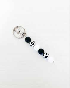 a key chain with black and white balls attached to it on a white table top