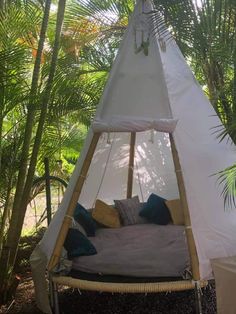 a teepee tent with pillows on it in the middle of some plants and trees