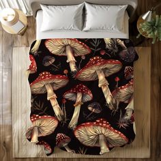 a bed covered in a black and red comforter with mushrooms on the ground next to it