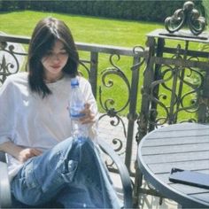 a woman sitting on a bench with a bottle of water in her hand and looking at the camera