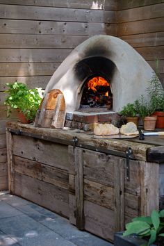 an outdoor pizza oven with potted plants and bread