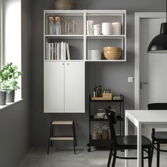 a kitchen with white cabinets and black chairs next to a dining room table in front of a window