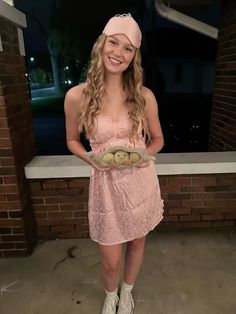 a girl in a pink dress holding some cookies