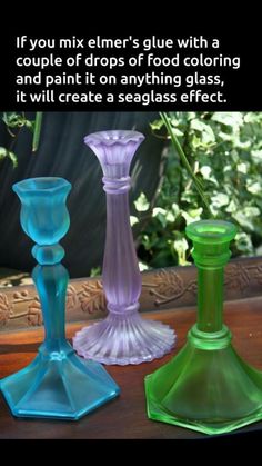 three different colored glass vases sitting next to each other on top of a table