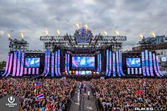 a large group of people standing in front of a stage with lights and banners on it