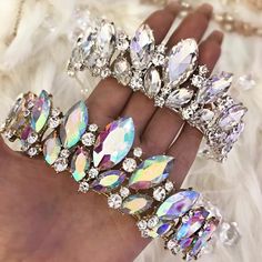 a woman's hand holding several crystal bracelets