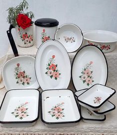 a table topped with lots of white plates and bowls filled with flowers on them next to a potted plant