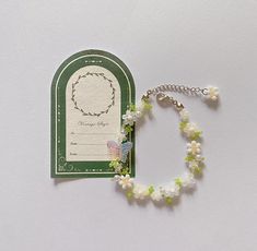 a white bracelet with green beads and a tag on the side that says happy baby